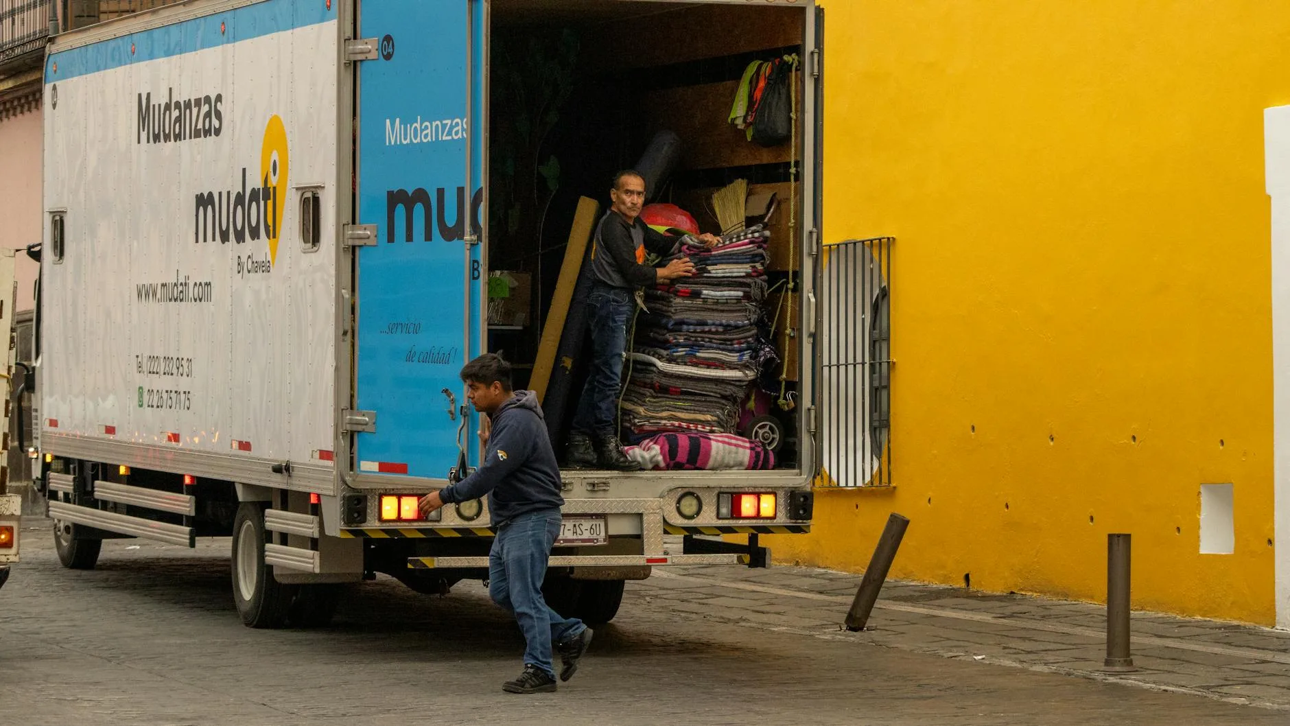 Déménageurs chargeant des affaires dans un camion de déménagement garé dans une rue