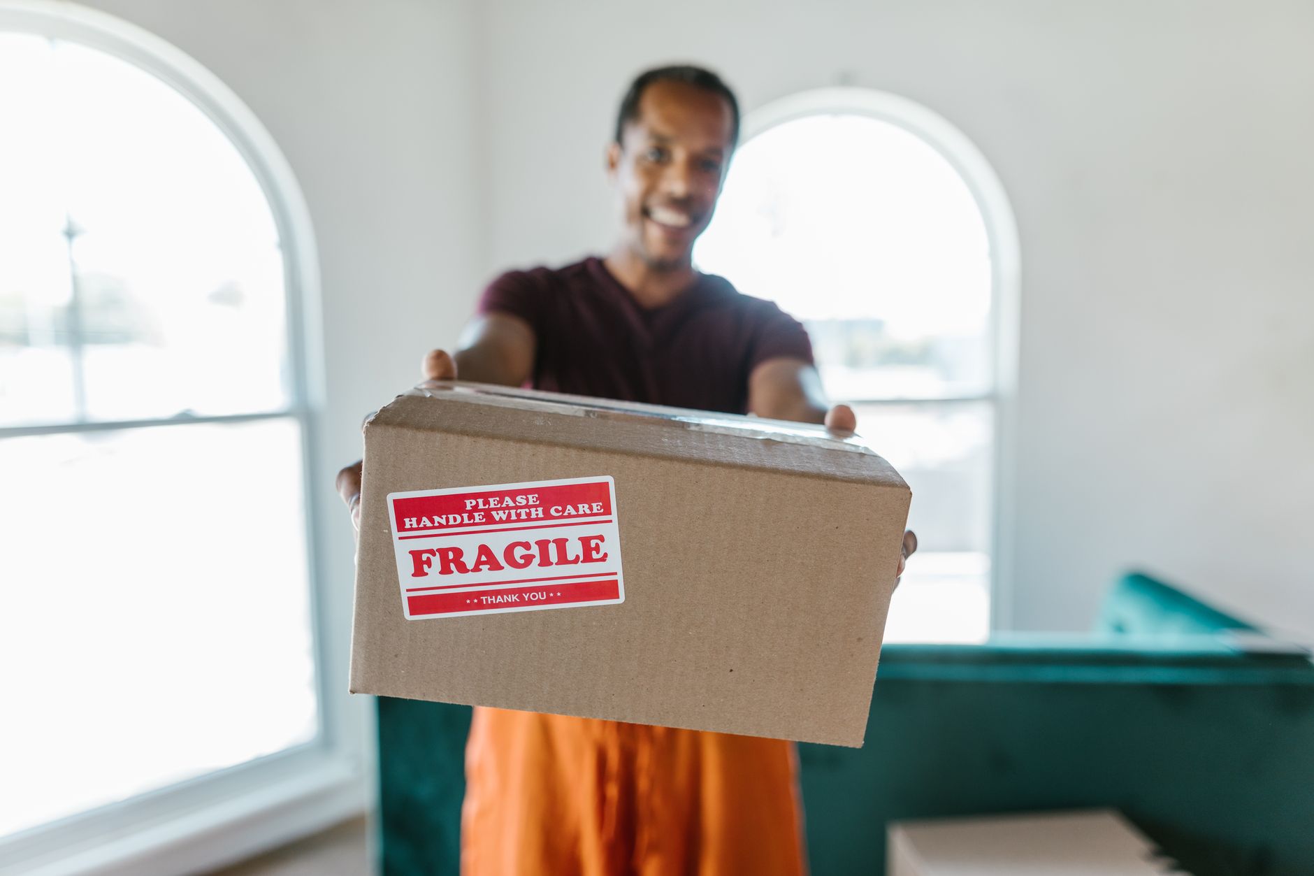 Déménageur professionnel portant un carton étiqueté dans un couloir d'appartement
