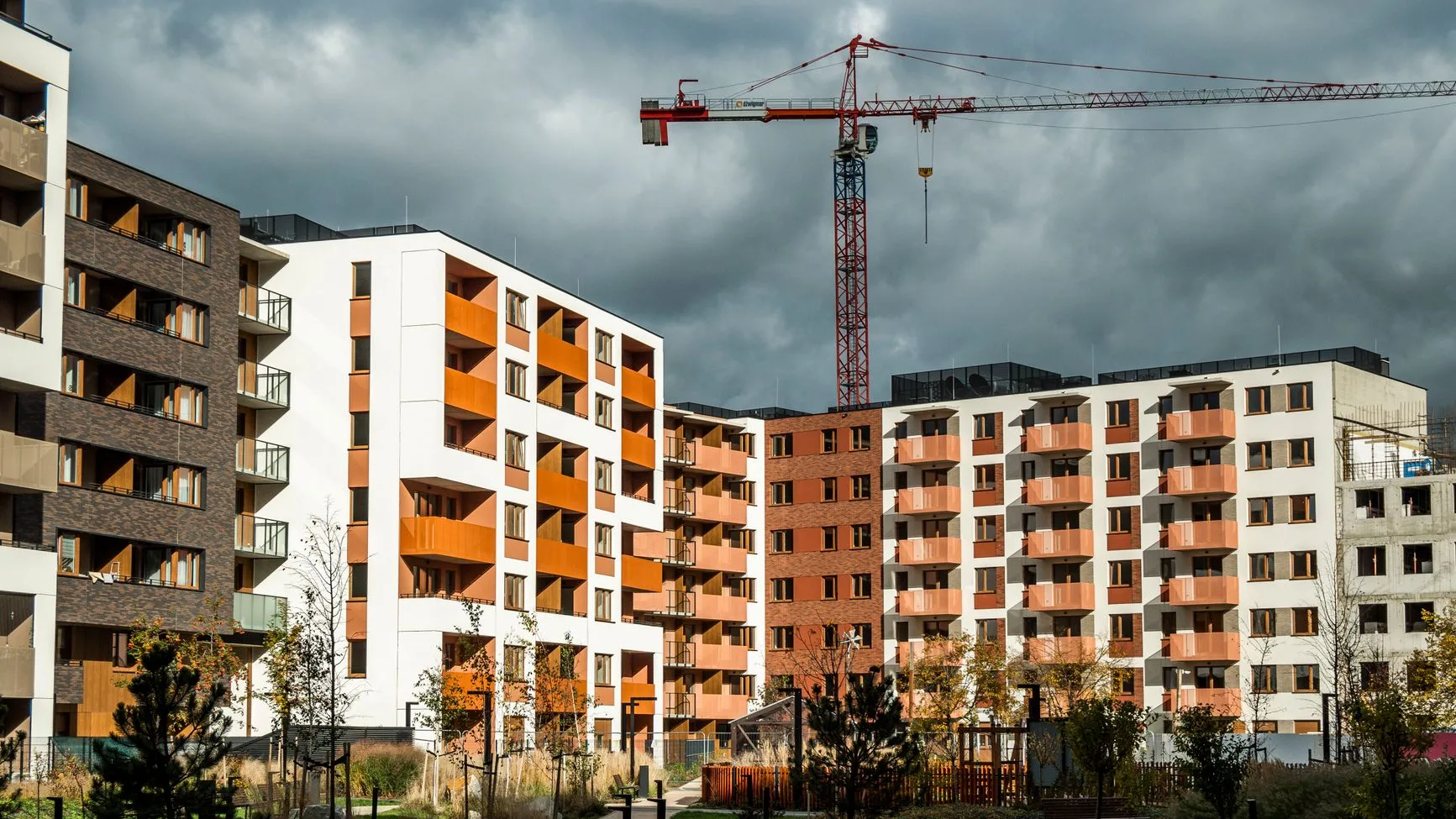 Résidence neuve avec balcons orange et grue de chantier en arrière-plan